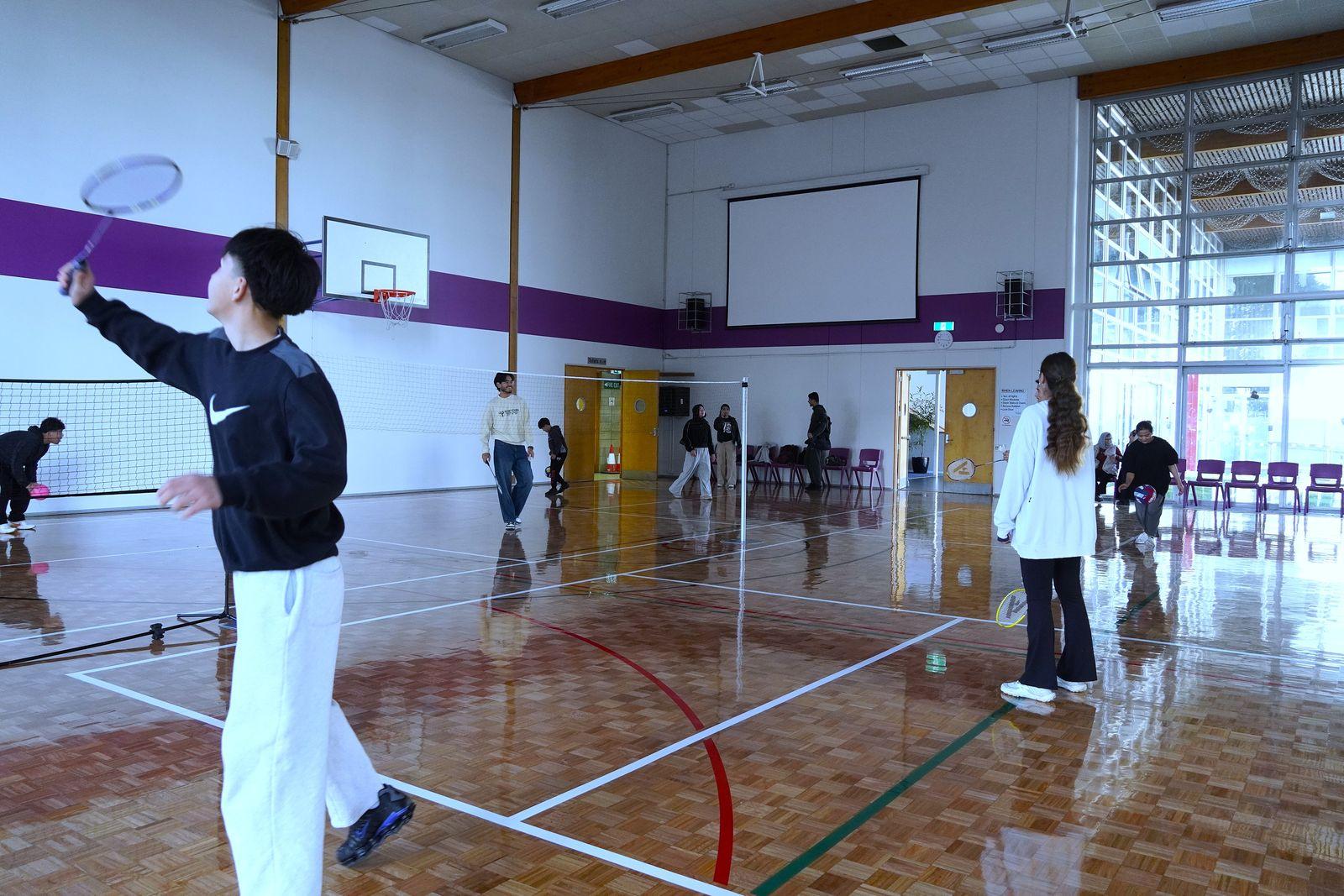 A player mid-swing in the foreground while games run on the courts behind